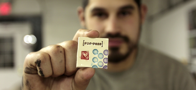 David Wilson, Kent State alumnus proudly displays a small gift given to him by a family friend on his first official day of business at his new design studio, Downpour Creative. Wilson keeps this “success” magnet on his desk hoping it sets the tone for his first year in business. Photos by Eddie Olschansky.