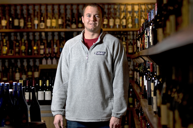 Wes Stein, junior construction management major, stands in one of the wine aisles at 101 Bottles of Beer on the Wall, located on 115 North Willow Street where he works, Tuesday. He also works as a full-time bee-keeper. Photo by Matt Hafley.