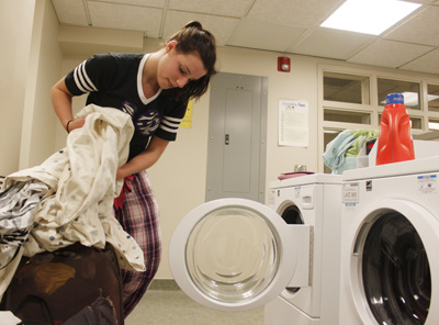 Sophomore fashion design major Anna McCann loads a laundry machine in Centennial Court E on Wednesday. She is pleased that students will have to pay a $40 laundry fee per semester instead of having laundry cards. "That would be so nice because I know I have spent way over 40 bucks," McCann said. Photo by Jessica Yanesh.