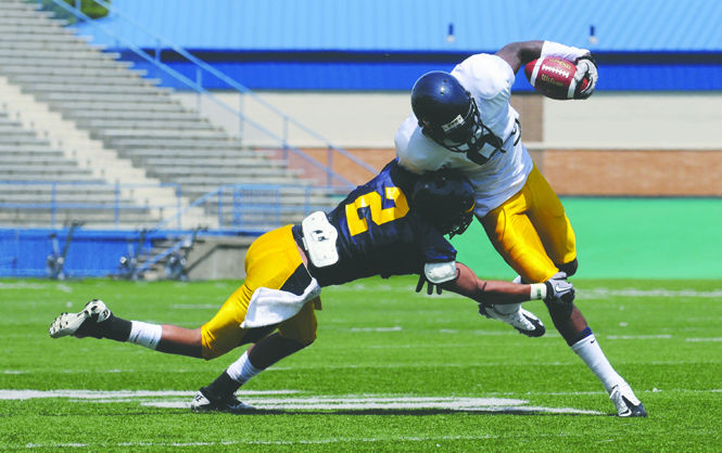 Cornerback Josh Pleasant tackles wide receiver Matt Hurdle during preseason practice while being supervised by new head coach Darrell Hazell. The Flashes start out the 2011 season in Alabama Saturday, Sept. 3. Photo by Philip Botta