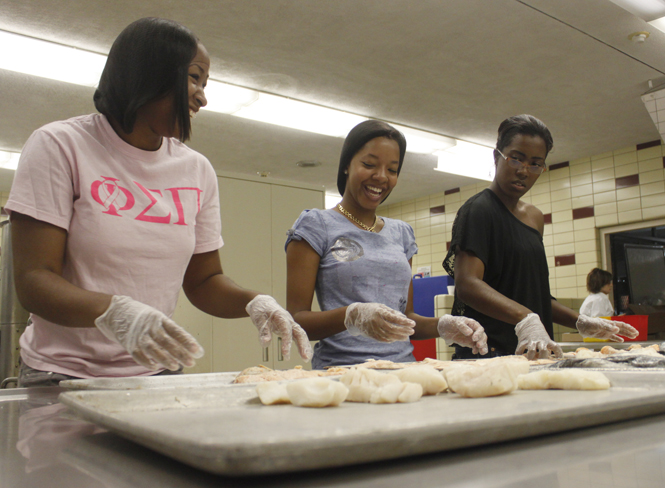 Senior fashion major Robin Johnson, senior fashion major Tanise Brown and junior nursing and psychology major Nycole Cox worked the salmon station in the Campus Kitchen on Wednesday, September 21. The Campus Kitchen is a volunteer program where students recover old but still good to use food and turn it into hot meals for Kent Social Services, a local soup kitchen. Photo by Jessica Yanesh.