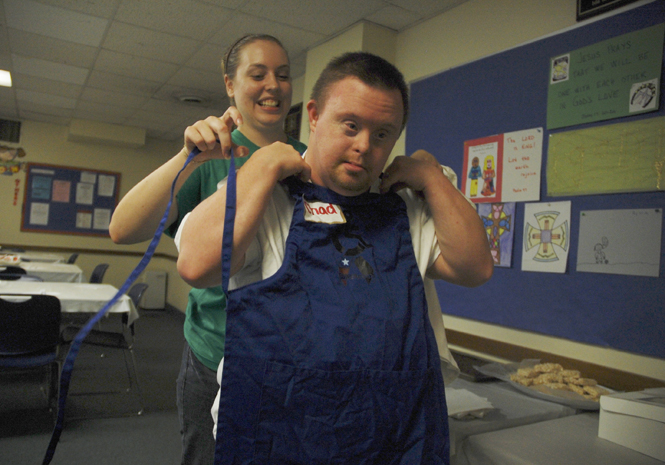 Ashleigh Stewart, of Youngstown, puts an apron on Chad Howe, of Kent at the third annual Power Corps spaghetti dinner on Sept. 9. Stewart has been with Power Corps for five years and has been the program manager for three. "I love to see the interaction between members and participants," Stewart said. Photo by Nancy Urchak.