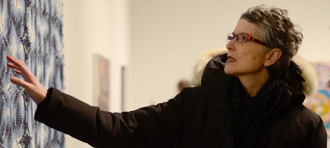 Janice Lessman-Moss, Professor of Textile and Weaving, at the opening of the Faculty Art Gallery in the Art Building Thursday. Lessman is pointing to her piece, titled" #397 Only Passing Through/Blue." Photo by Jacob Byk.