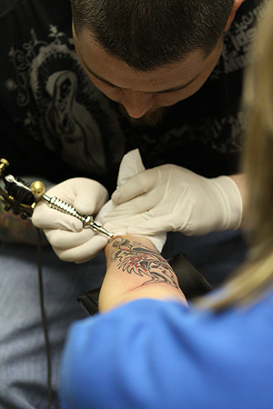 Jake Davis, of Smokin' Tattooz on the corner of Main and Water street, finishes up a tattoo on Lauren Repp, 24, of Las Vegas on January 30. Photo by Coty Giannelli.