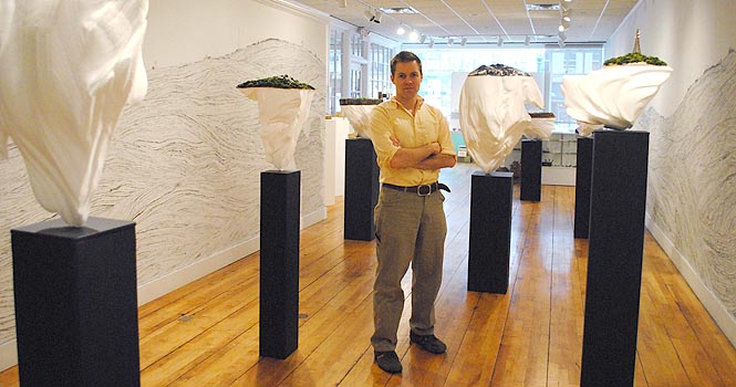 Professor Mark Schatz stands with art work in his exhibit "Steady As She Goes" in the Kent State School of Art's Downtown Gallery on Tuesday, Feb. 7. Schatz said the exhibit is inspired by scenery from the midwest and its ever changing forms. The exhibit will be on display until Feb. 11. Photo by Jenna Watson.