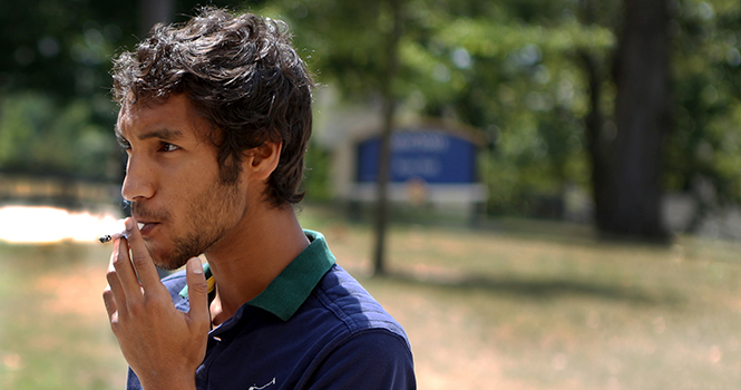 Psychology and pre-denistry major Mohammad Al Khuzamia smokes a cigarette outside of Kent Hall on Saturday. Photo by Coty Giannelli.