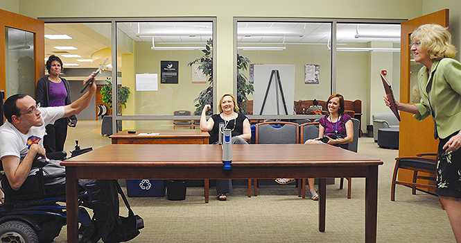 Tony Snyder, inner library loans employee, serves the ball to Mary Lovin during the Kent State Office Olympics in the “Wimbledon Ping Pong” game. Office employees played ping pong with hardcover library books Tuesday, July 17. Photo by Philip Botta.