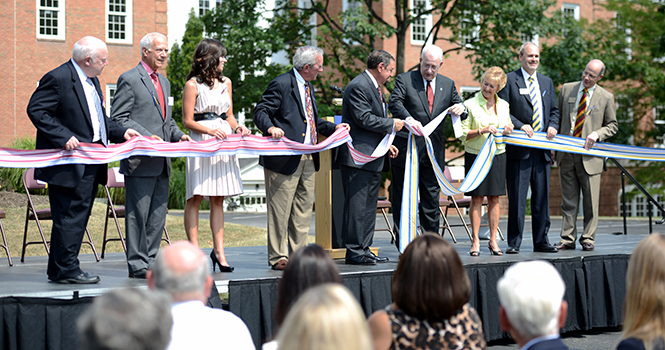 President Lester Lefton and Dean Thomas V. Melillo tie a ribbon, symbolizing the College of Podiatric Medicine becoming a college at Kent State on Aug. 8. Photo by Matt Hafley.