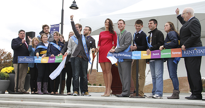 Evan Gildenblatt, executive director of Kent State’s Undergraduate Student Government, cheers toward the crowd after cutting the ribbon during the dedication ceremony for the new Student Green in front of Risman Plaza Thursday. Construction began on the site in early April and concluded in October. The area provides more space for students to relax as well as a performance stage for student organizations. Photo by SHANE FLANIGAN.