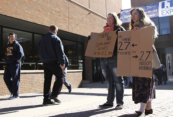 Freshman fashion design major Jasmine Summers (right) and sophomore early childhood education major Katie Fife (left), hold up signs between the student center and KIVA to raise awareness for enslaved people on Tuesday, March 5 as part of the International Justice Mission KSU chapter's 27-hour demonstration at Risman Plaza. Photo by Shane Flanigan.