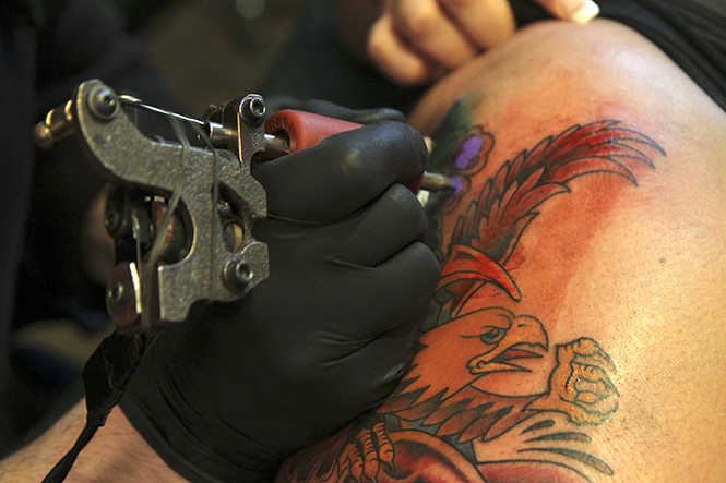 Tattoo artist Larry Spano, 32, of Kent works on a piece inside Defiance Tattoos in downtown Kent on Saturday, April 6. Spano has been working at the Kent shop for almost four years. Photo by Shane Flanigan.