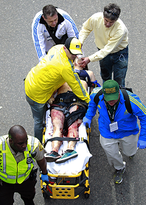 Medical workers aid an injured man at the finish line of the 2013 Boston Marathon following an explosion in Boston, Monday, April 15, 2013. Two bombs exploded near the finish of the Boston Marathon on Monday, killing two people, injuring 22 others and sending authorities rushing to aid wounded spectators, race organizers and police said. Photo by Charles Krupa, AP.