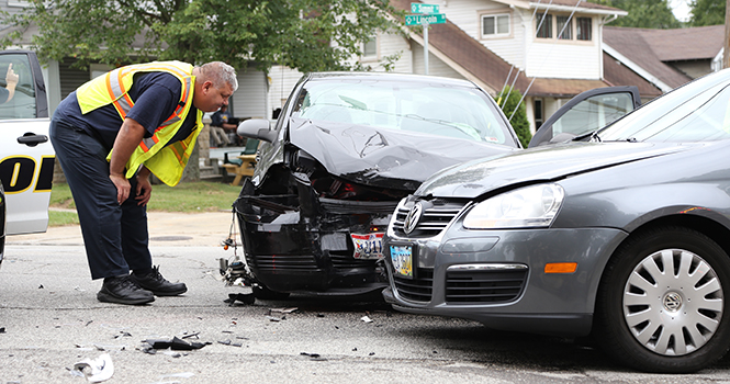 A Kent City fireman looks at the two cars crashed at the interestion of Lincoln and East Summit Street on Sept. 3, 2013. Photo by Brian Smith.