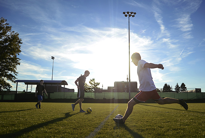 (From left) Freshman biology major Troy Kotsch, freshman biology major Caleb Cameron and sophomore architecture major Paul Blatner kick soccer balls Thursday evening at one of the two new recreational fields located on Loop Road off of East Summit Street across from the Recreation and Wellness Center. The fields are for students' recreation as well as practice areas for some club sports. Photo by Jenna Watson.