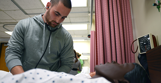 Sophomore nursing students Justin Kaczmarek practices taking a pulse on a mock patient in the Sim Lab on Wednesday afternoon, Nov. 6, 2013. The mock patients allow nursing students to practice taking blood pressure and pulse and also have lung sound and arrhythmias. Photo by Leah Klafczynski.