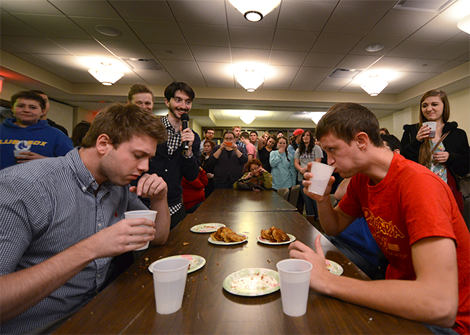 Ben Woolf, an international ambassador for Alpha Epsilon Pi from England (left), and Kent State senior physical education major Matthew Weaver (right) participate in a latke eating contest at AEPi's annual LatkeFest at Hillel on Thursday, Nov. 21, 2013. Woolf defeated Weaver with a tie breaker, consuming a total of nine latke cakes. All of the fifth annual festival's funds will go to Save a Child's Heart, a cause that benefits children in need of transplants. Photo by Jenna Watson.