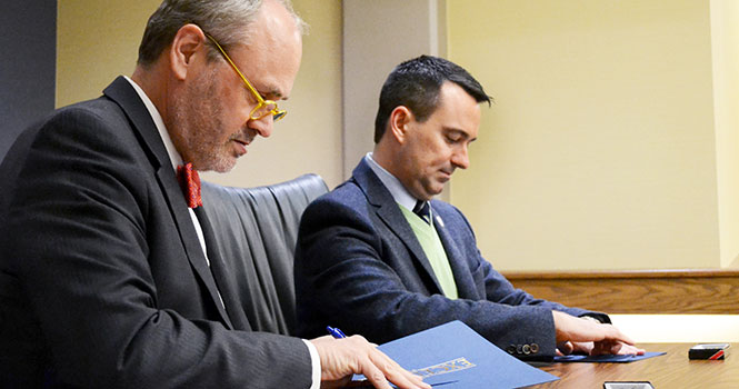 Provost Todd Diacon (left) and Dr. Charles Taylor, Dean of NEOMED College of Pharmacy, (right) prepare to sign the agreement policy allowing students to eventually transfer to the Kent NEOMED program and graduate sooner.