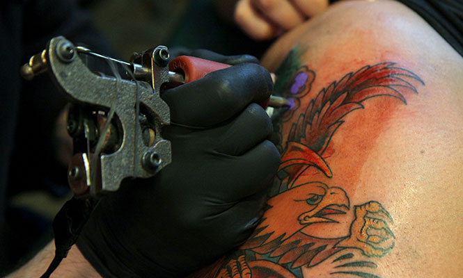 Tattoo artist Larry Spano, 32, of Kent works on a piece for Amanda Burkhart, 21, of Streetsboro, inside Defiance Tattoos in downtown Kent on Saturday, April 6, 2013. Spano has been working at the Kent shop for almost four years.