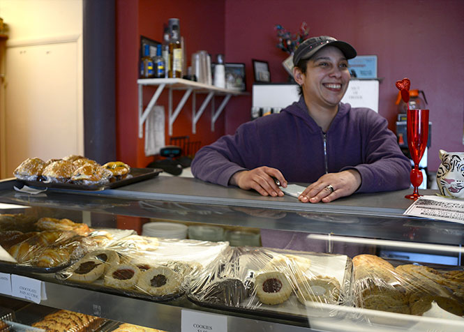 Andrea Berry, owner of Baked in the Village cafe downtown, talks to customers Wednesday afternoon, Feb. 12, 2014. Baked in the Village will participate in the Chocolate Walk downtown Saturday, giving away chocolate brownie cookies, pictured center in the display case.