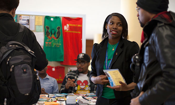 Senior health car administration major Eriane Matthews hands AmeriCorps VISTA Coordinator a packet at the HIV/AIDS Awareness event, Thursday, Feb. 6, 2014. Numerous pamphlets line the event table intended to spread awareness of HIV/AIDS in the black community.