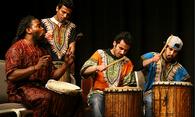 Term instructor of Pan-African studies Olu Manns (left) performs on stage with students from his Cultural Expressions class. Manns was quoted "On the One" referring to the diversity of students in his class being brought together from nations all across the world during the 19th annual African Night, Friday, March 14, 2014.