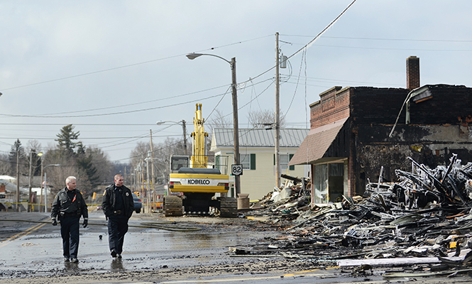 Two Garrettsville emergency personnel review damage along Main Street, Sunday, March 23, 2014, after the prior day's fire burned 13 businesses to the ground.