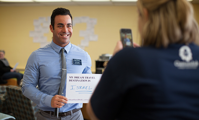 Employee for the Office of Global Education Nick Vasiloff holds up his sign saying his dream place to travel would be Israel at the "I (Heart) Travel Week" event in the Kent State library Wednesday, Feb. 12, 2014.