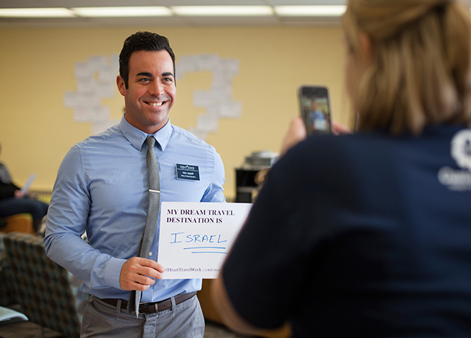 Employee for the Office of Global Education Nick Vasiloff holds up his sign which reads that his dream place to travel is Israel, at the I Love Travel Week event in the Kent State library Wednesday, Feb. 12, 2014.