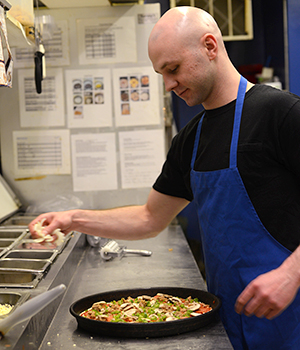 Guy's Pizza cook Brandon Smith makes a pizza in the kitchen, April 9, 2014.