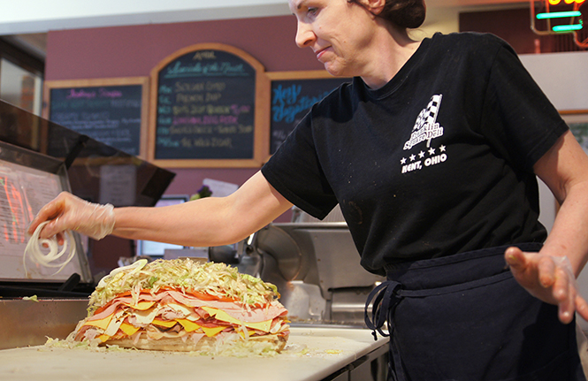 Jill Wymer tops "the Destroyer" sandwich with onions before holding it together with the necessary four toothpicks, April 6, 2014.