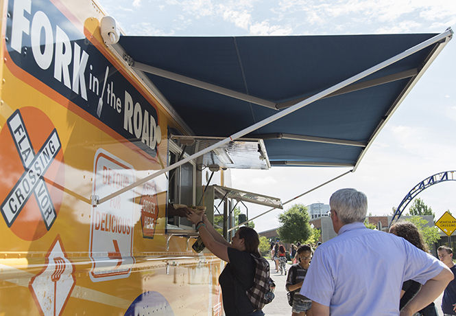 Senior visual communication design major Lynsey Simonette grabs her lunch order from Fork in the Road, a new food truck on campus. Lynsey bought an order of loaded fries topped with cheese, pulled pork and green onions.