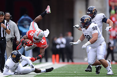 Ohio State's Ezekiel Elliott dives over Kent State's Demetrius Monday while running the ball at the OSU vs. KSU football game at Ohio Stadium on Saturday, Sept. 13, 2014. The Flashes fell to the Buckeyes 66-0.