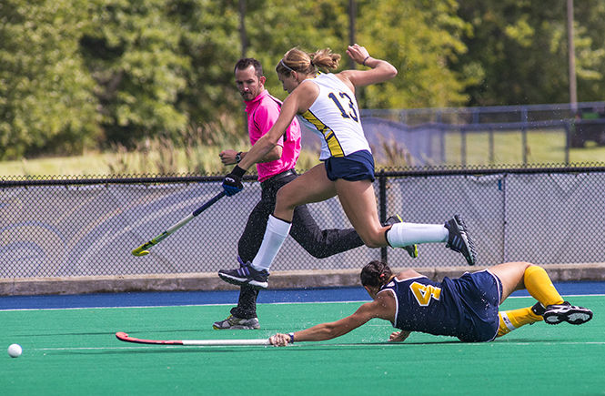 Kent State senior forward Hannah Faulkner fails to steal the ball as Michigan's Mackenzie Ellis jumps to maintain possession at the field hockey game Sunday, Sept. 21, 2014. The Flashes lost to Michigan 3-2.