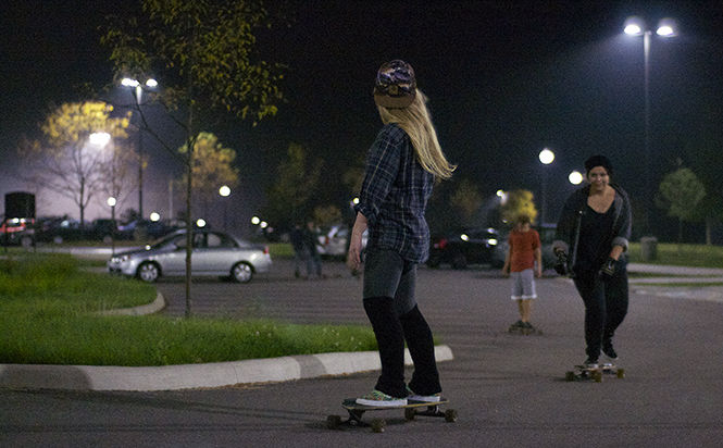 Katie Welles / The Kent Stater Kent State Longboarding club founder, Isabella Luzader, and Lisa Olszewsski, senior VCD and cellular biology major, take a ride around the parking lot for the first "meeting" of the Kent State Longboarding Club on Wednesday, Oct. 1, 2014.