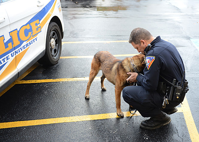 Officer Miguel H. Witt praises bomb dog Dexter in the parking lot of the Kent State University Police Department on E. Summit Street on Monday, Nov. 24, 2014. Dexter will partner with Officer Witt and Coco, a 3-year-old German Shepherd that became Kent State’s first police dog last fall.