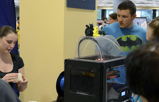 The Kent Stater Senior broadcast journalism major Lauren Blue, explains to students how the 3D printer in the multimedia studio works in the Kent State library.