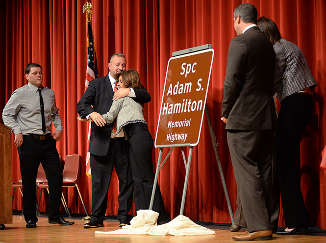 Scott Hamilton hugs his wife, Connie Hamilton, after unveiling the road sign dedicating part of Route 43 to his late son Adam Hamilton at Kent Roosevelt High School on Tuesday, Nov. 11, 2014. Adam Hamilton died during his tour in Afganistan on May, 28, 2011.