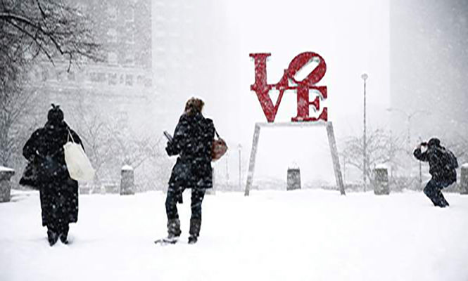 AP PHOTO People visit John F. Kennedy Plaza, also known as Love Park during a winter snowstorm Tuesday, Jan. 21, in Philadelphia. A storm is sweeping across the Mid-Atlantic and New England. The National Weather Service said the storm could bring 8 to 12 inches of snow to Philadelphia and New York City, and more than a foot in Boston.