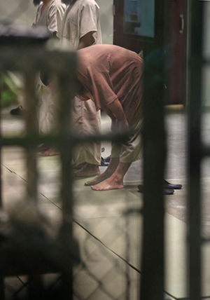 A Navy captain has been fired and is being investigated in connection with an alleged affair with a woman on the base and the recent death of her husband. The captain was in charge of the naval station at Guantanamo Bay, Cuba, where this trio of captives kept in communal lockup at the base are seen at prayer on Tuesday, Nov. 4, 2014, in this image that was cropped to pass review by the U.S. military.