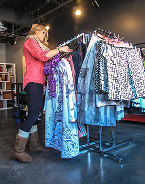 Alex Logsdon, a senior fashion merchandising major organizes clothing at the Kent State Fashion Store in Acorn Alley on Thursday Feb. 5, 2015. " I would love to work for Ralph Lauren someday" said Logsdon who has been working at the store for almost a year.