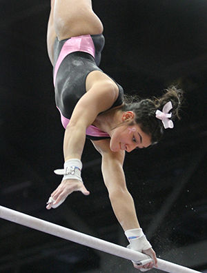 Freshman Michaela Romito grabs the bar while competing in the uneven bars during the Flip for a Cure meet against George Washington on Sunday, March 1, 2015.