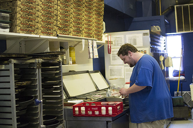 Ben Faulhaber pours marinara sauce into cups at Guy’s Pizza on Saturday April 4, 2015. Guy’s Pizza is a popular pizza place in Downtown Kent.