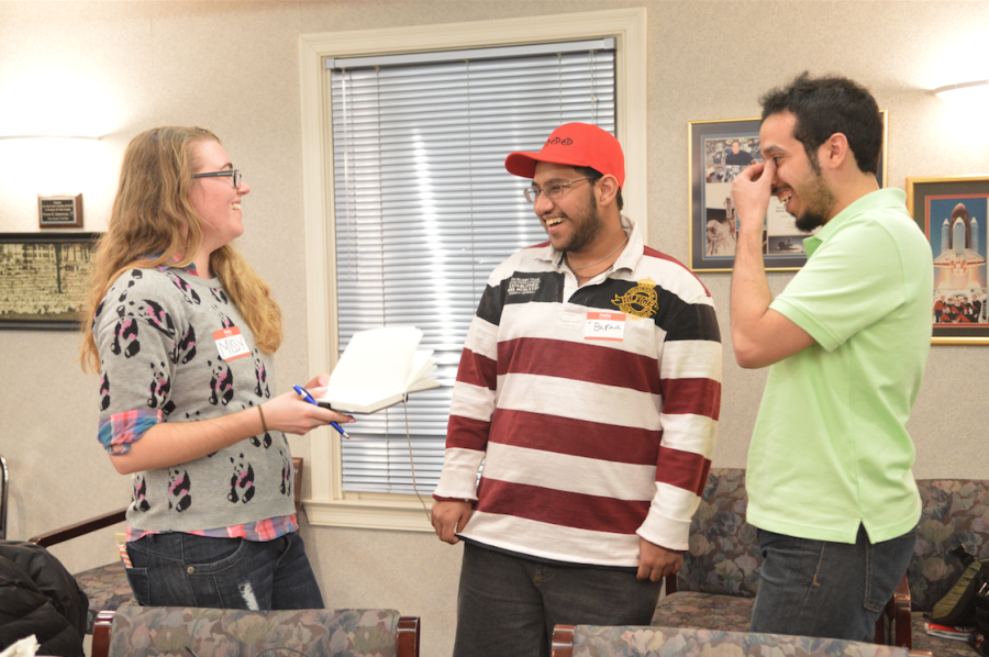 Missy Hendrix, a public health major, passes a book to students Baraa Iskandar and Abdullah Almotairi at the Kent State International Student Mentor's Meeting on March 3, 2015. Members of the organization can leave a message in their language in the journal to share with the group. 