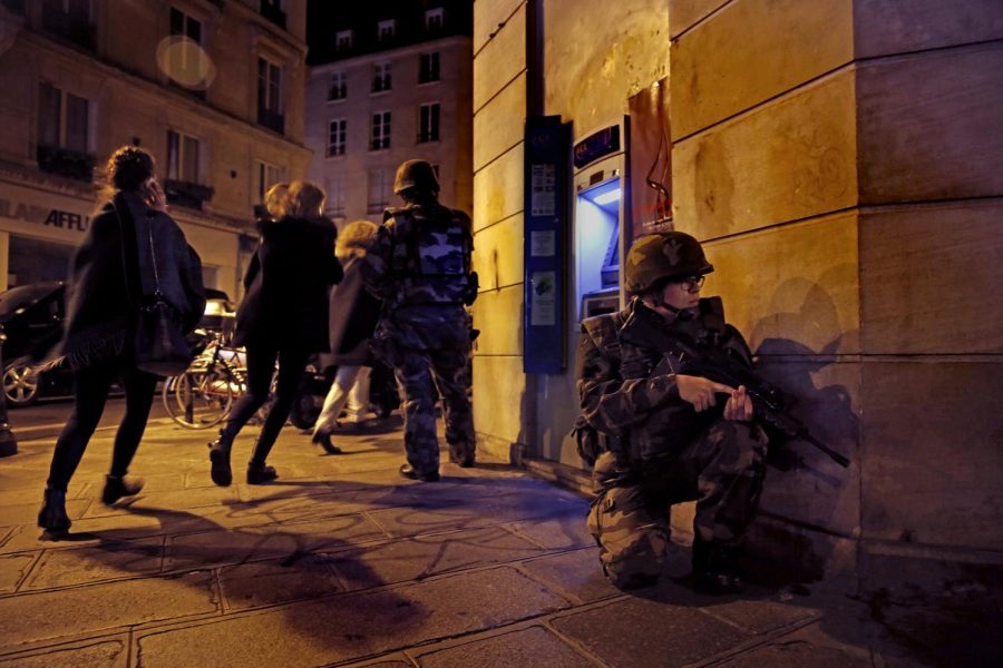 Women run past French soldiers on Sunday, Nov. 15, 2015, as panic spread through the streets of Paris when rumors of a car bomb surfaced. It turned out to be a car left running in the street. (Carolyn Cole/Los Angeles Times/TNS)