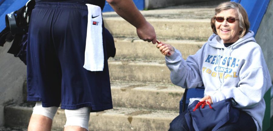 “Granny,” 77, hands out licorice sticks to members of the Kent football team as they leave the field after practice on Oct. 7, 2015.