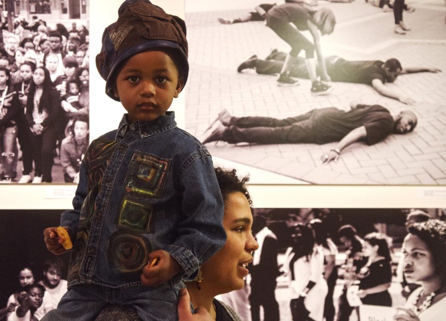 Kent State graduate Jennifer Cline and her 3 year-old son, Kwadwo Cline, attend Timothy Moore’s picture exhibition, “Get on the BUS: A Pictorial of Black Student Protest at KSU,” at the Uumbaji Gallery of Oscar Ritchie Hall on Saturday, Feb. 20, 2016.