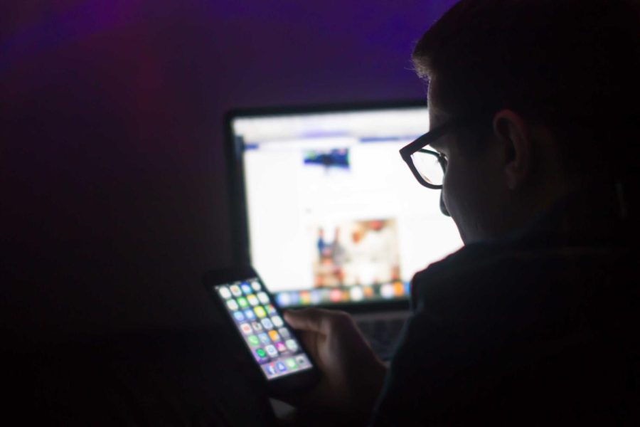 Mario Fasolo, a senior visual communication design major, looks at his phone in the dark on Jan. 30, 2016.