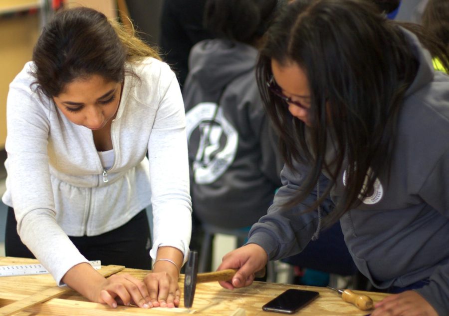 Senior interior design major Wadha Almatar helps 6th grader Danyelle hammer a nail into a piece of wood Saturday, March 5, 2016.