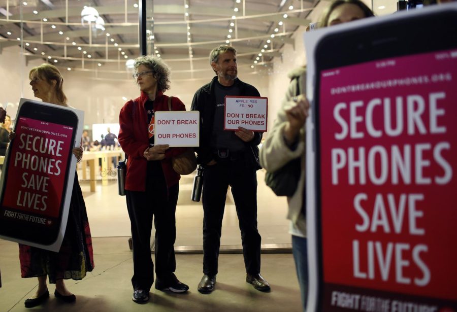 Protesters, from left, Sandra Bell, Victoria Best, and Charles Fredricks, hold signs in support of Apple store in Santa Monica, Calif., on Tuesday, Feb. 23, 2016. Rallies were planned at Apple stores across the country to support the company's refusal to help the FBI access the cell phone of a gunman who took part in the killings of 14 people at the Inland Regional Center in San Bernardino.