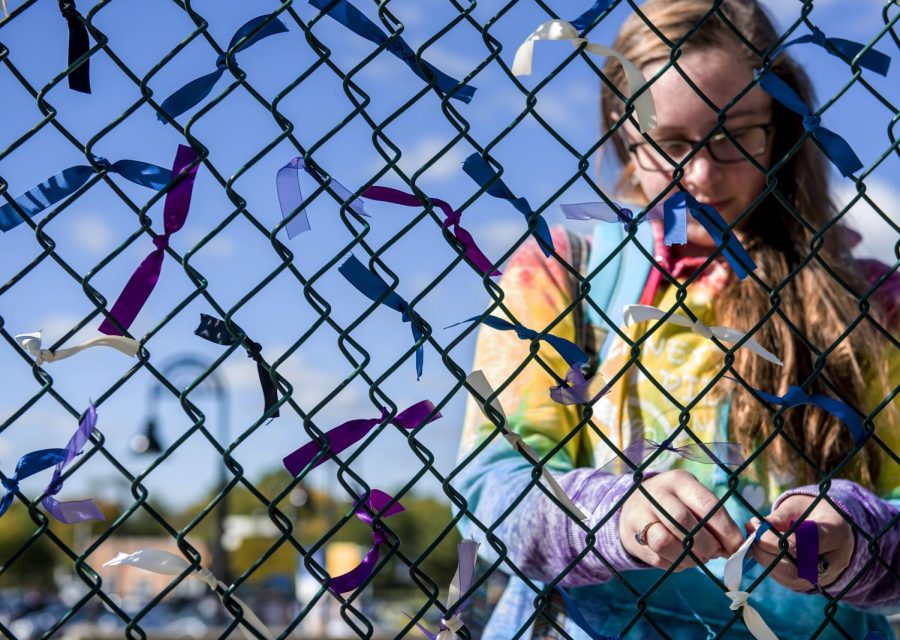 Freshman nursing major Rebekah Wareham ties a ribbon to a piece of fence in front of Kent State's M.A.C. Center on Monday, Oct 10, 2016 to signify that she is an ally of sexual assault victims. The student organization Students Against Sexual Assault allowed passersbys to tie a ribbon if they had been or knew of someone who had been a victim of sexual assault, domestic abuse, or stalking.